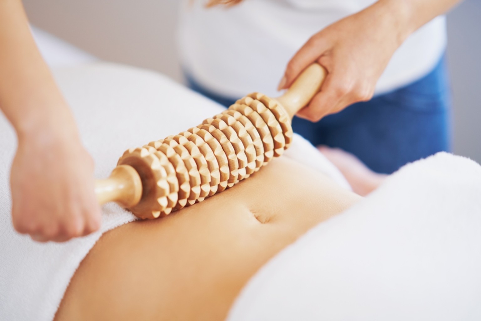 Massage van de buik met een houten Maderotherapie-roller